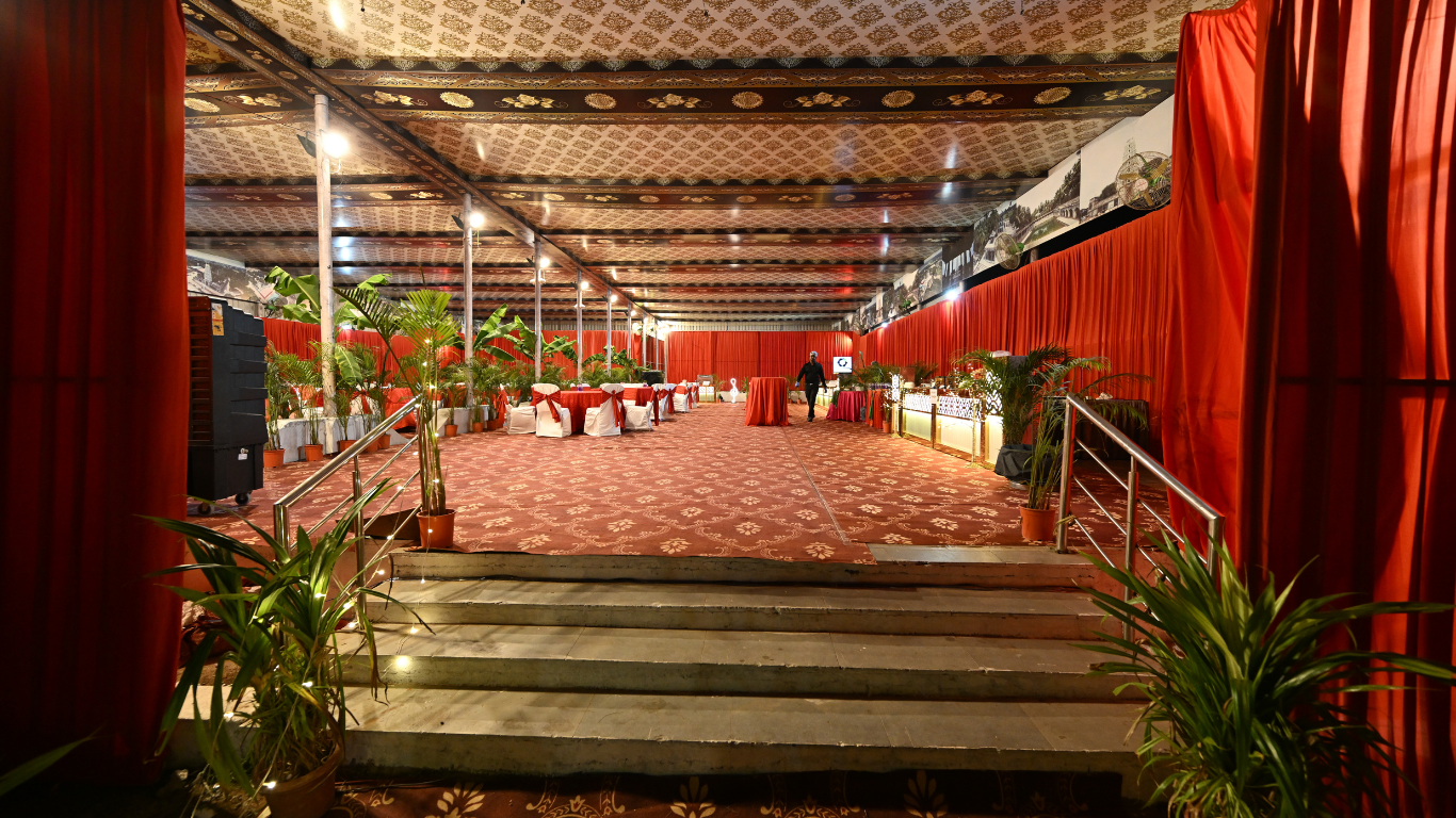Indoor reception sitting area with red drapes and banquet setup