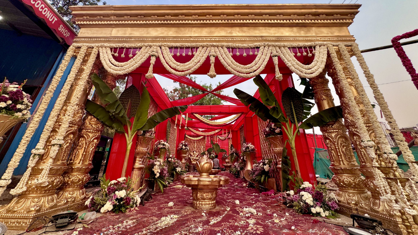 Grand floral wedding entrance with golden pillars and red canopy walkway