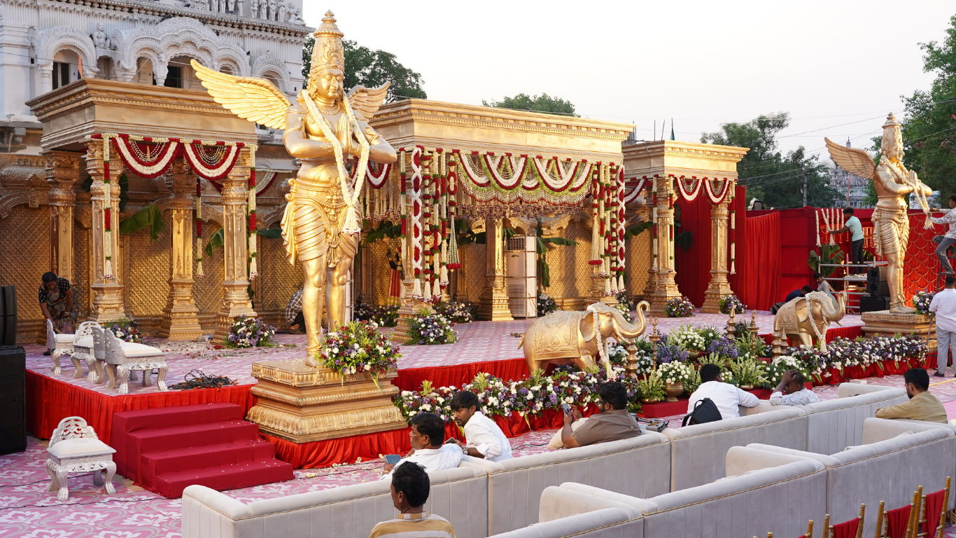 Side view of the grand golden wedding mandap with winged deity statues, elephants and floral garlands